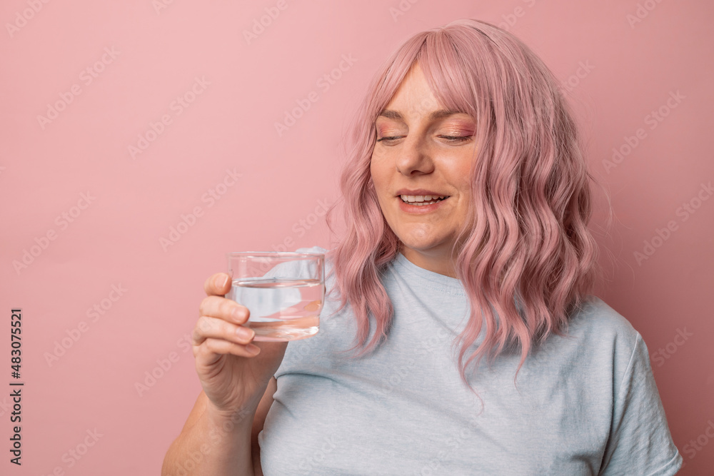 Beautiful young woman smiling while holding a glass of water Beautiful young woman smiling while holding a glass of water