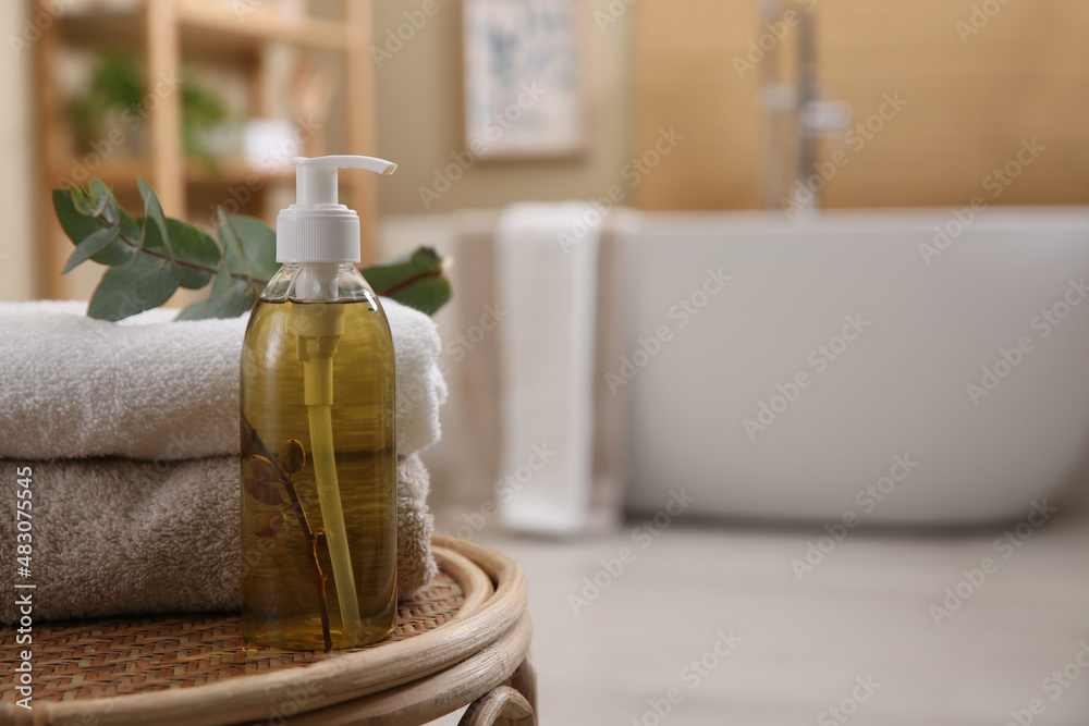 Dispenser of liquid soap, clean towels and eucalyptus branch on wicker stool in bathroom. Space for text Dispenser of liquid soap, clean towels and eucalyptus branch on wicker stool in bathroom. Space for text
