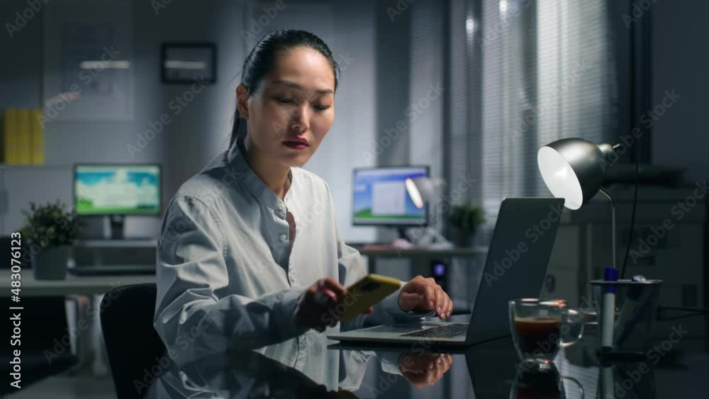 Asian entrepreneur receive bad news on smartphone working in office Asian entrepreneur receive bad news on smartphone working in office