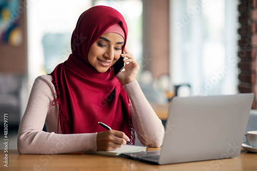 Positive middle-eastern lady in hijab having phone conversation