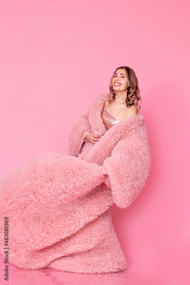Woman is a beautiful young adult model in the studio in a pink designer coat and on a pink background Woman is a beautiful young adult model in the studio in a pink designer coat and on a pink background