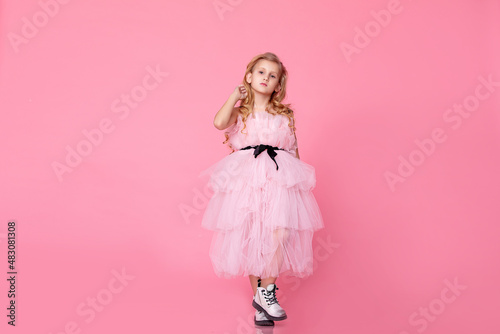 Child girl model in a pink dress on a pink background, fashionable, stylish