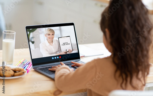 Little girl student have video call with adult caucasian woman teacher, math lesson on laptop screen at home