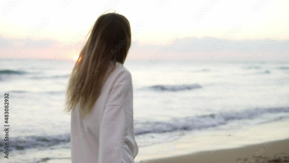 Happy woman walking along ocean coast in white suit, smiling and spinning around Happy woman walking along ocean coast in white suit, smiling and spinning around