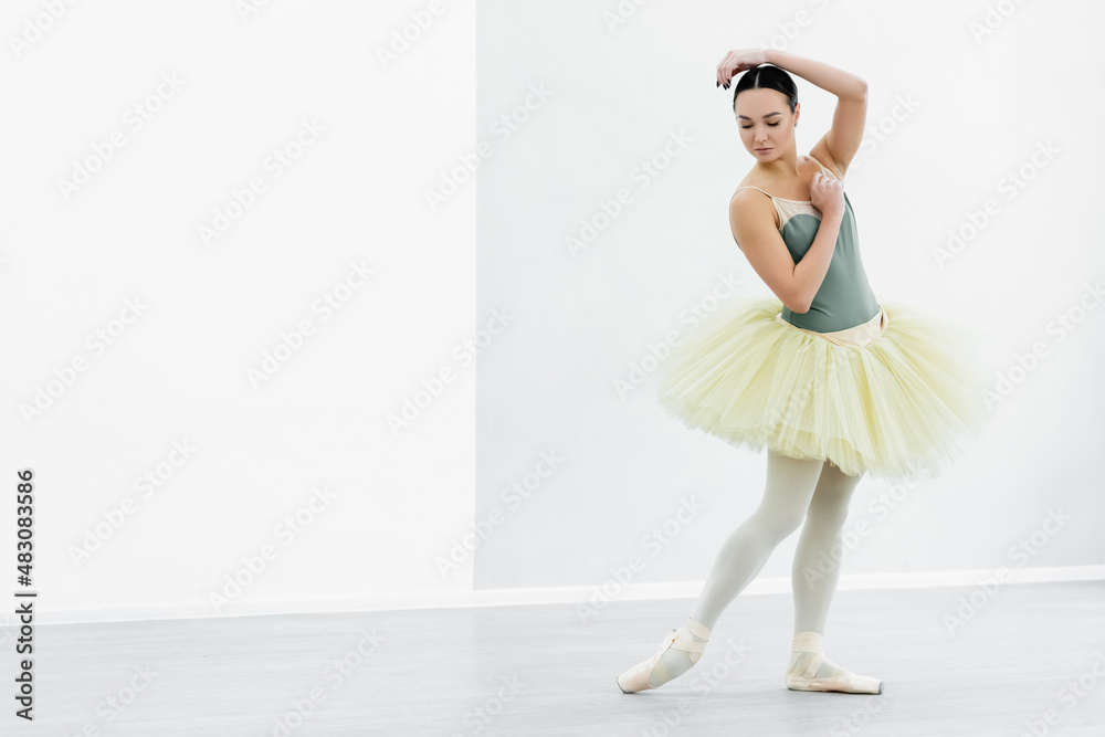 full length view of graceful ballerina in tutu dancing in studio