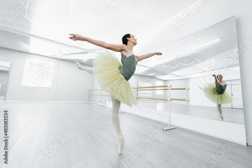 full length view of graceful ballerina dancing during repetition in studio