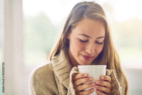 Having a cup of sereni-tea. Shot of a young woman enjoying a warm beverage at home.