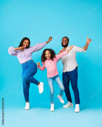 Portrait of emotional black family dancing at blue studio