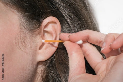 Woman cleaning her ear with plastic stick photo