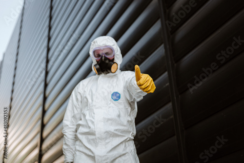 man in a protective suit in front of a building with yellow glowers