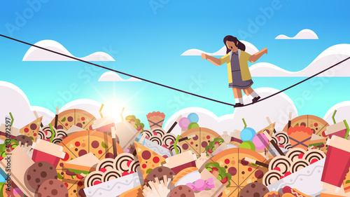 schoolgirl balancing on rope above junk food assortment of fast food unhealthy nutrition junkfood addiction concept