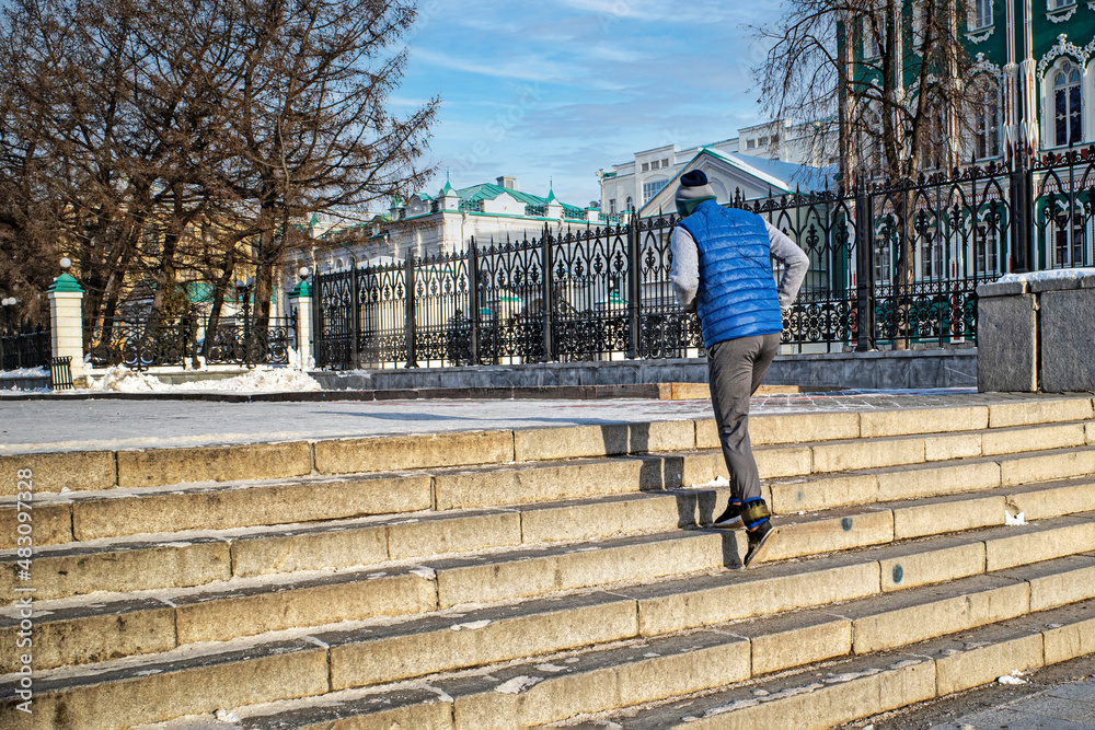 A man runs down the steps of the city embankment on a winter day