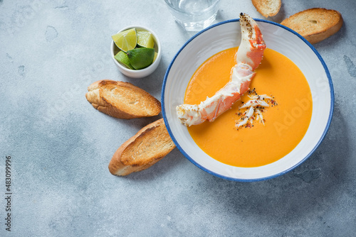 Plate of bisque with crab and baguette over light-blue stone background, high angle view, horizontal shot with space photo