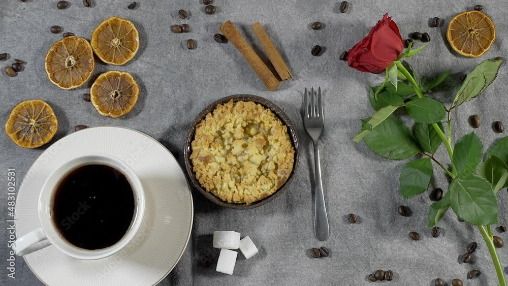 coffee, on the table coffee beans with cinnamon, apple pie and dried oranges lie on a brown background. and rose