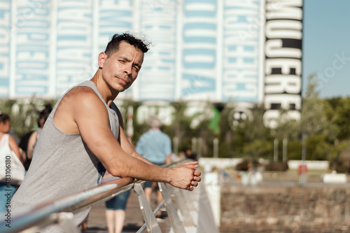 sporty latin young man on a bridge in the city looking at the camera with copy space