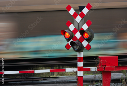 Train passes at crossing with red signal and closed barriers. 