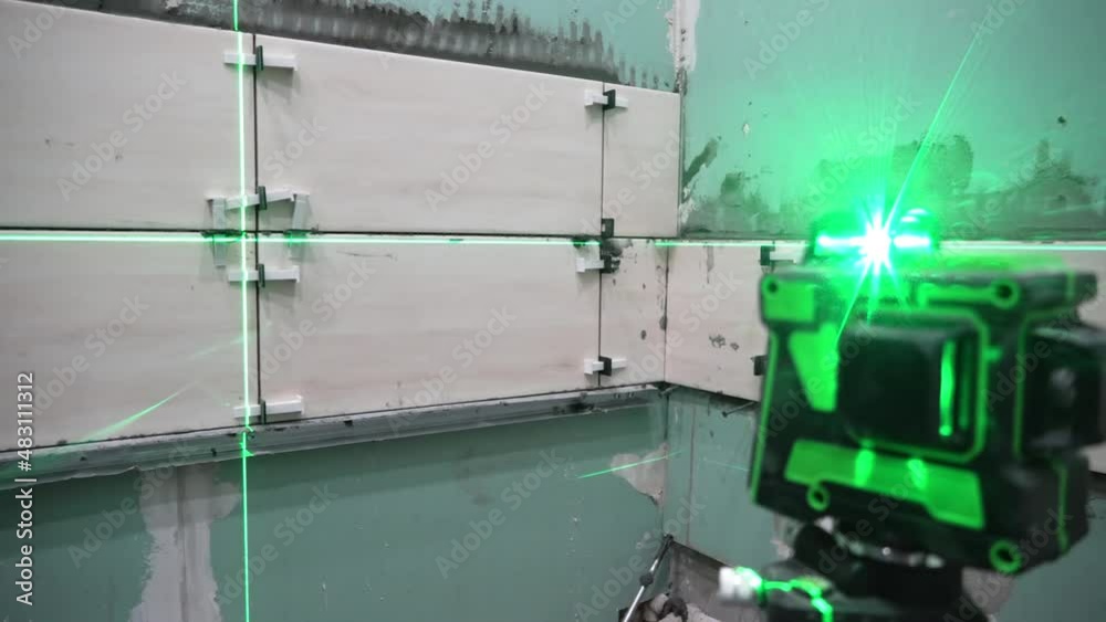 Construction and repair of walls in a new building.Laying wall tiles using a construction level and a laser level. Renovation in the house. Perform calculations and measurements using a laser Construction and repair of walls in a new building.Laying wall tiles using a construction level and a laser level. Renovation in the house. Perform calculations and measurements using a laser