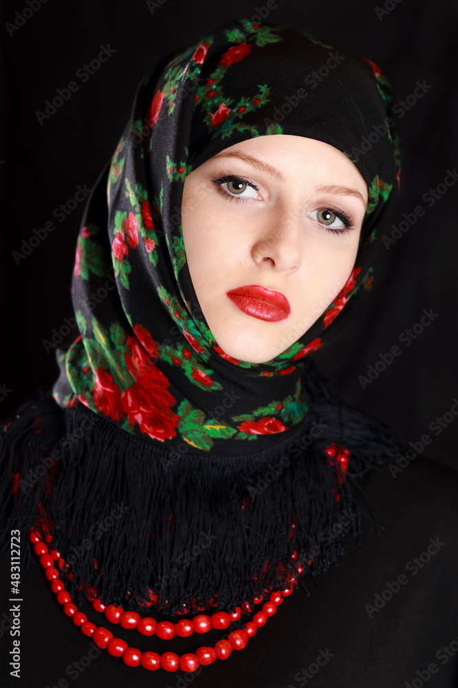 Portrait of fashionable young Woman with perfect make up in colorful shawl on her head .Gorgeous young Woman with red lips. Attractive young Ukrainian Girl in a ethnic handkerchief with a red necklace
