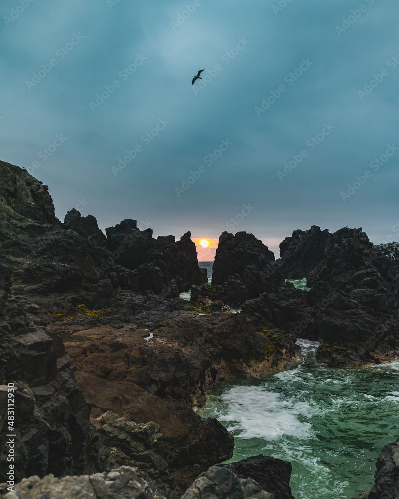 Naklejka premium sunset between beach rocks