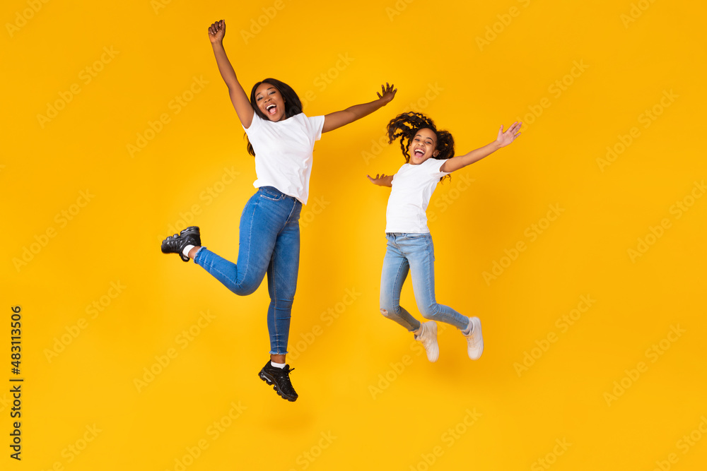 Portrait of emotional black family of two jumping at studio