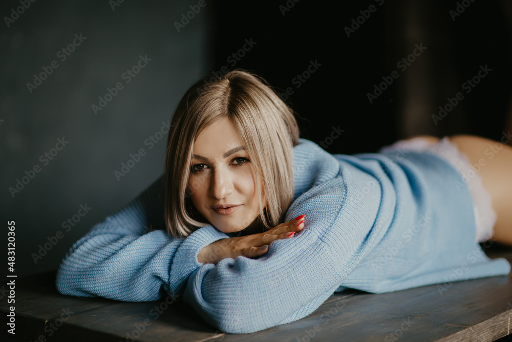 blonde girl in a blue sweater lies on the table blonde girl in a blue sweater lies on the table