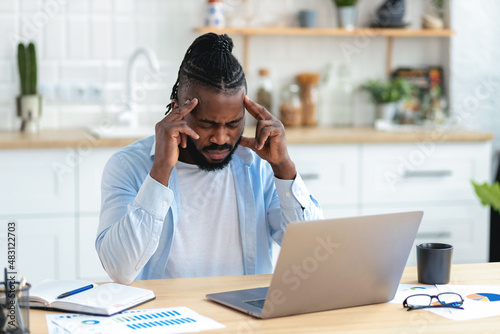 African American businessman freelancer suffering from severe headache after working at the computer for a long time, migraine, emotional stress. Man massaging his whiskey