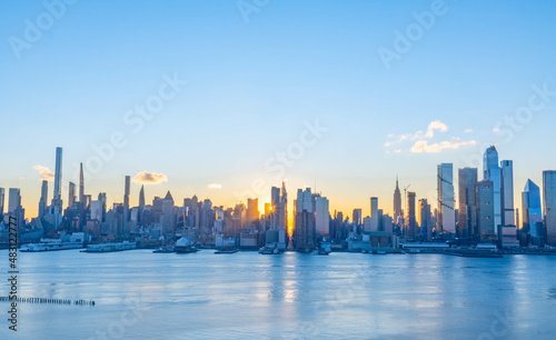 Stunning sunrise over Manhattan skyline with saturated colors and sun rays camping from the sun.