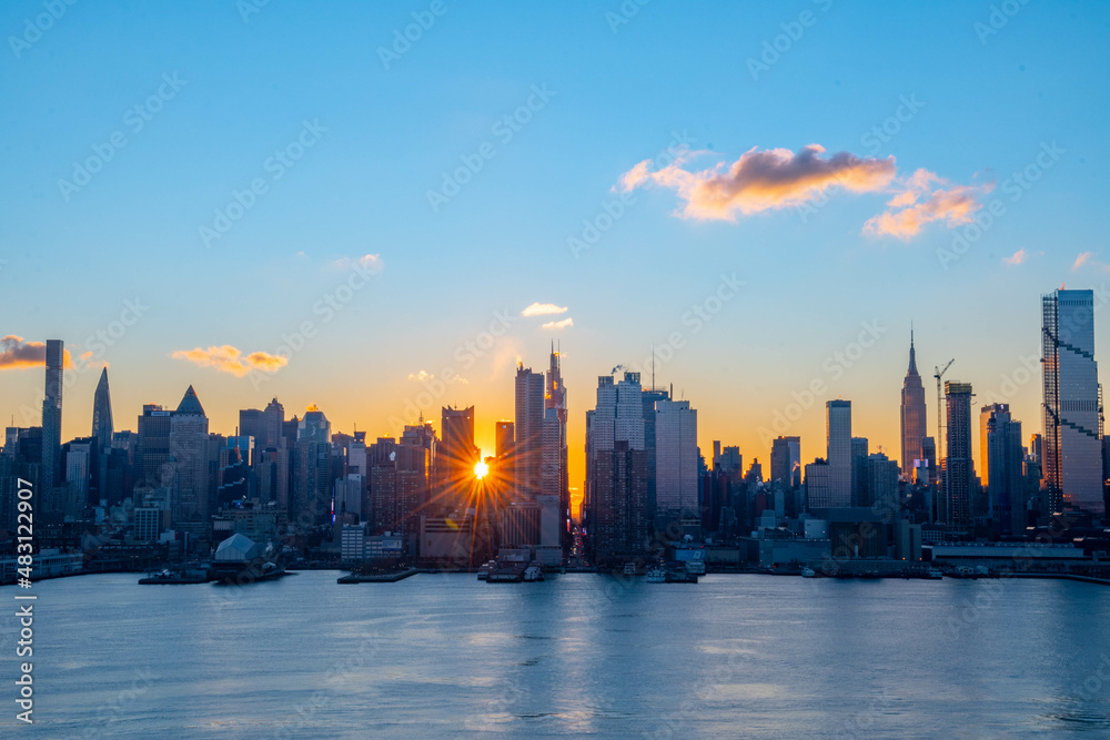Obraz premium Stunning sunrise over Manhattan skyline with saturated colors and sun rays camping from the sun.
