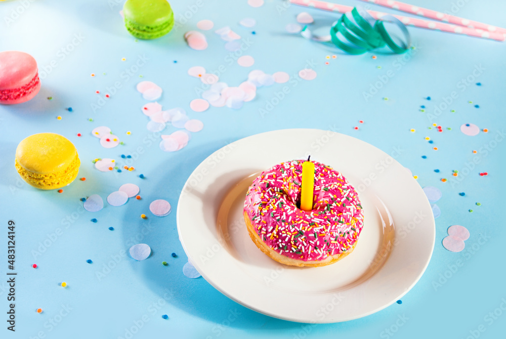 Delicious donut with pink icing and candle confetti macaroons on the background. Birthday concept. Delicious donut with pink icing and candle confetti macaroons on the background. Birthday concept.