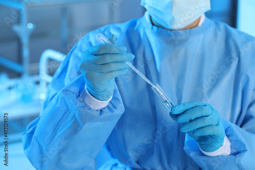 Scientist dripping sample into test tube in laboratory, closeup. Medical research