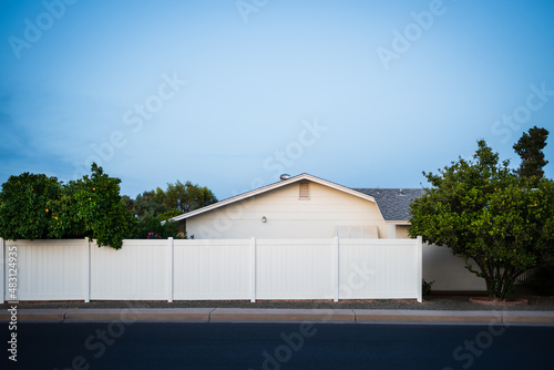Side view of a white brick house with white vinyl fencing in Sun City, Arizona