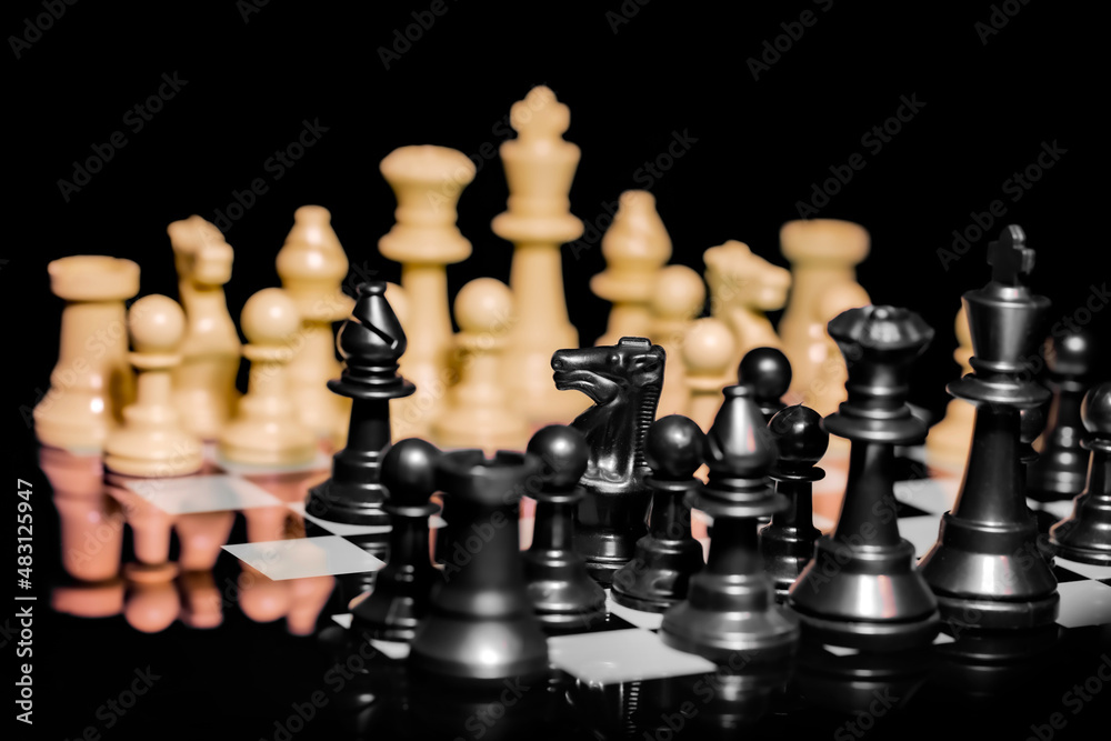 Close up of Chess pieces on a reflective mirror board surface with black background