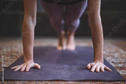 Close up on woman hands performing Phalakasana or High plank. Young girl doing meditation performing yoga at home. Healthy life style concept. 