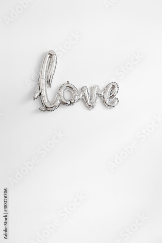 the word love hanging on a wall in silver balloon letters