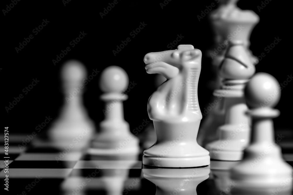 Close up of Chess pieces on a reflective mirror board surface with black background Close up of Chess pieces on a reflective mirror board surface with black background