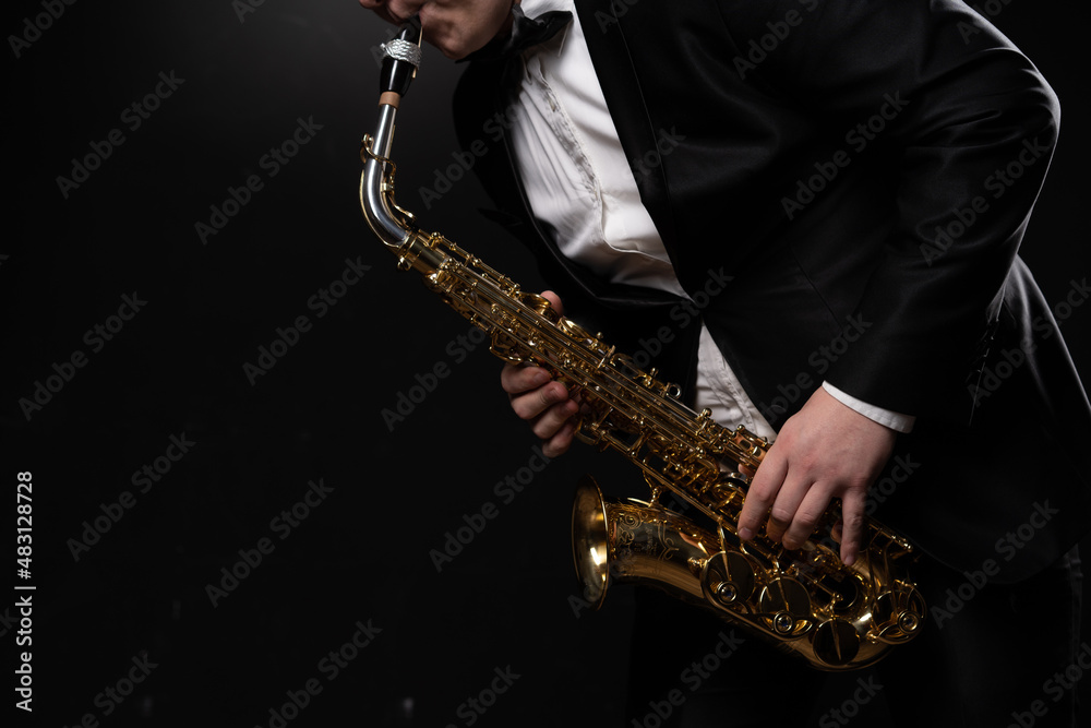 Naklejka premium Saxophonist Musician in Black Tuxedo and Bow Tie Plays the Alto Saxophone. Alto Sax Player, Jazz Sazophonist. Black Background. Close-up. Copy Space . High quality photo