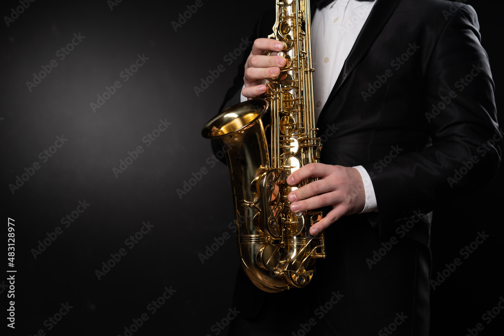 Naklejka premium Saxophonist Guy in Sunglasses Plays the Tenor Saxophone, Musician Blows the Saxophone. Selective Focus on Bell of Saxophone. Blurred Background, Neon Light. High quality photo