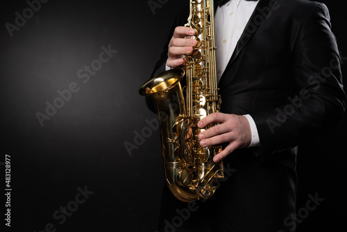 Saxophonist Guy in Sunglasses Plays the Tenor Saxophone, Musician Blows the Saxophone. Selective Focus on Bell of Saxophone. Blurred Background, Neon Light. High quality photo