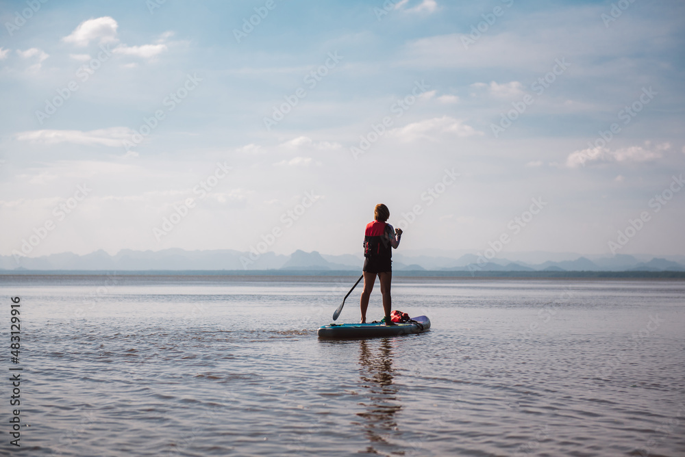 Young asian woman with safety vest on stand up paddle board.