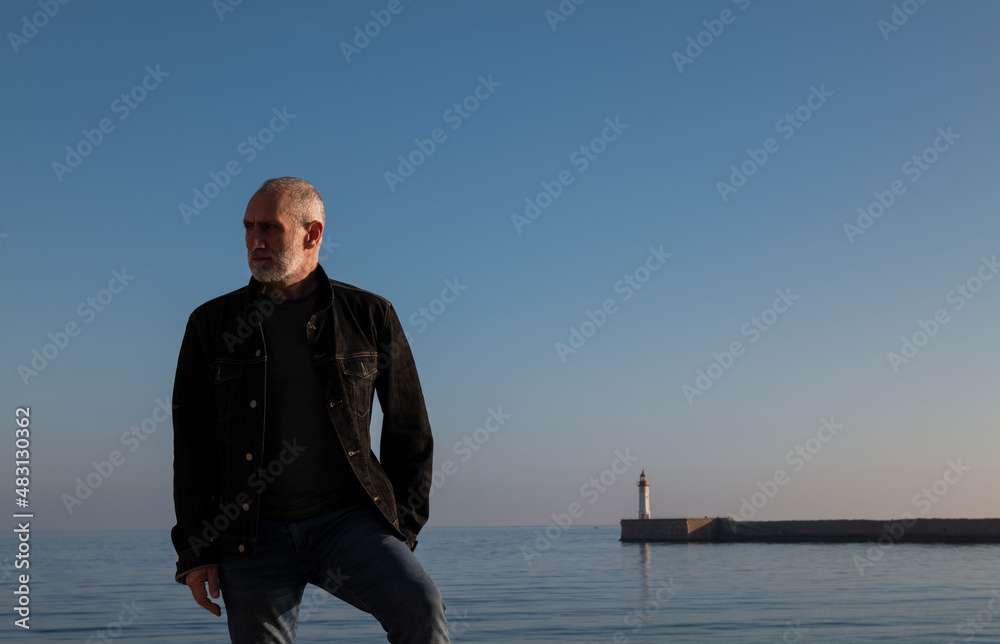 Adult man against sea and sky with lighthouse in background. Almeria, Spain