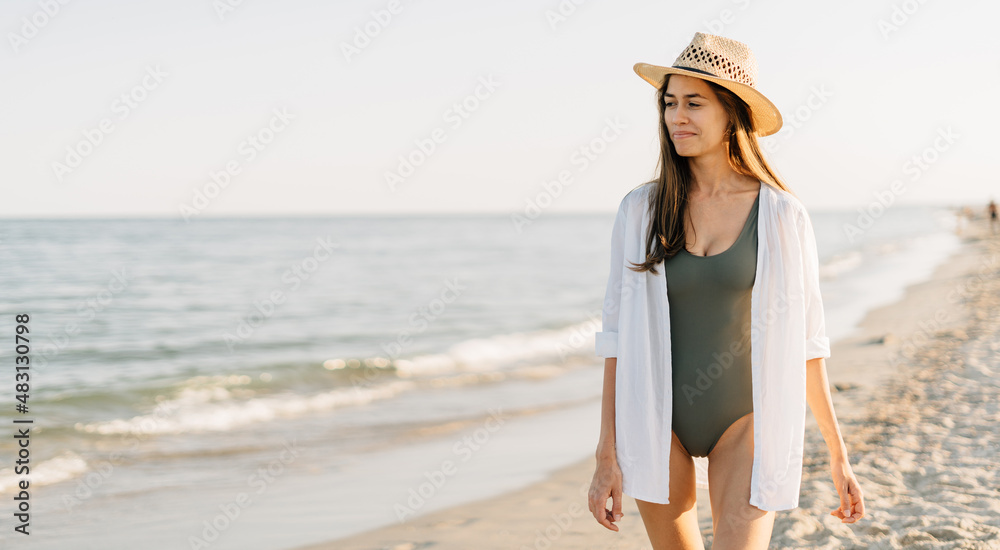Happy young woman feeling the breeze on the beach. The young lady is doing well and enjoying freedom at sea. Banner.