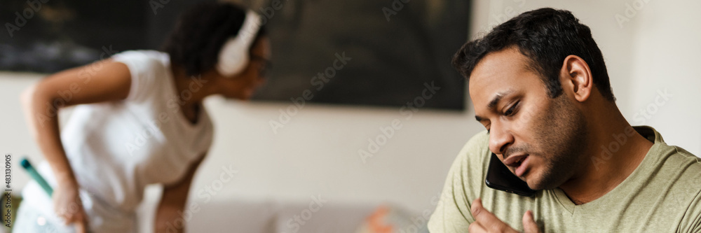 Obraz premium Middle eastern man talking on mobile phone while working with laptop