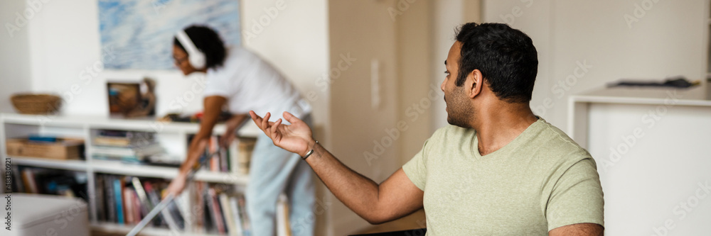 Fototapeta premium Middle eastern man working with laptop and talking with his girlfriend at home