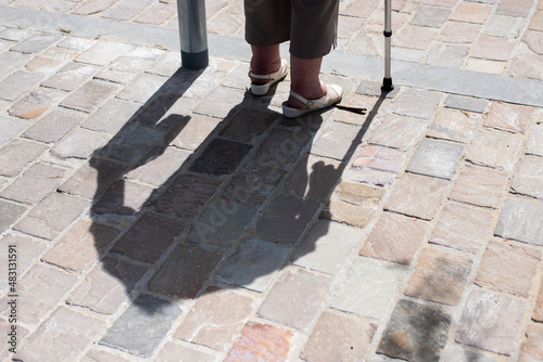 Shadow and legs of an elderly woman with a walking aid