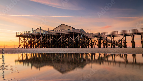 Pile dwelling is reflected in the water at sunset by the sea