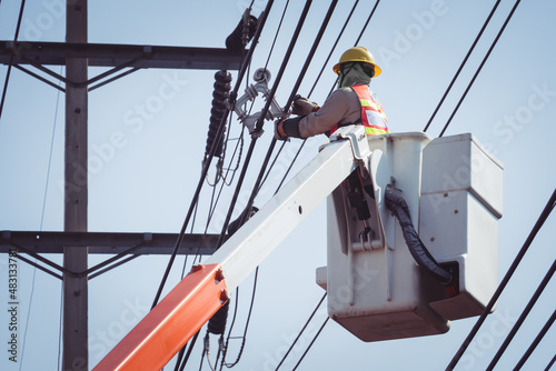 Electrical power line technicians perform maintenance on power lines by using a truck-mounted bucket.