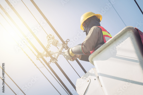 Electrical power line technicians perform maintenance on power lines by using a truck-mounted bucket.