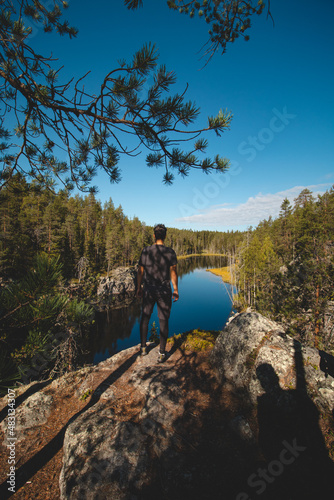 traveller aged 24 is lying on a high rock and observing a beautiful natural lake in hiidenportti National Park, Sotkamo in kainuu region, Finland. Hiking the Finnish countryside photo