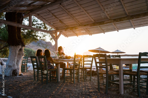 Family enjoying dinner in a restaurant on the beach at sunset.