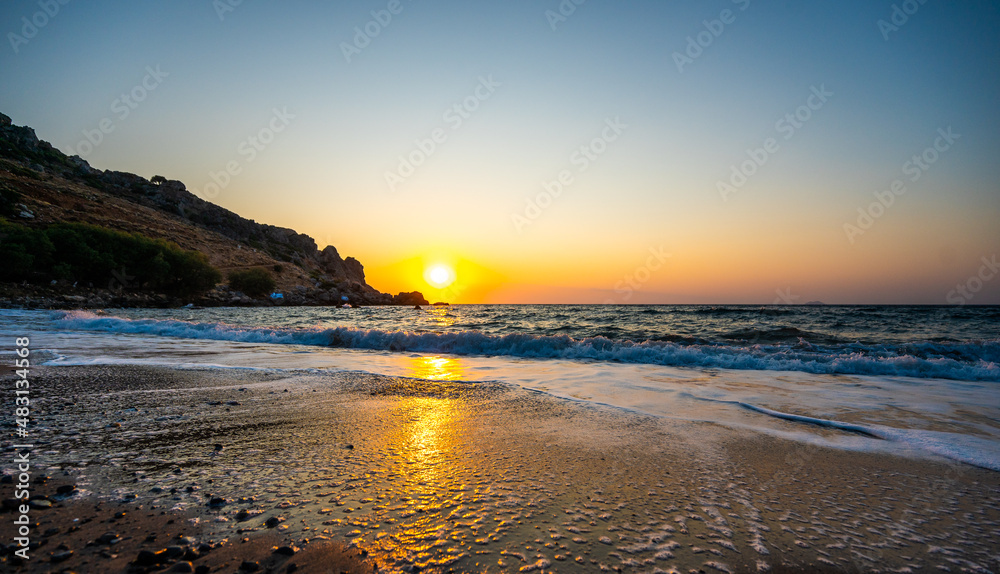 Amazing sunset on a sandy beach in Crete, Greece.